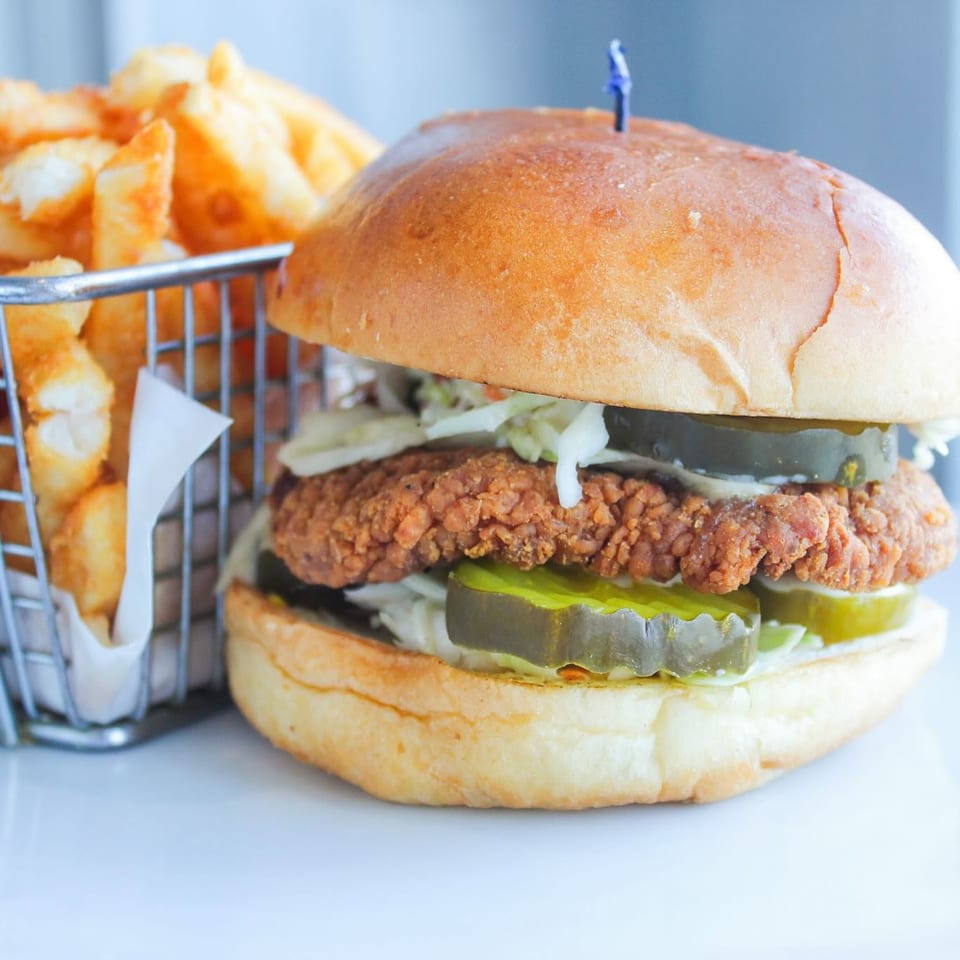 Crispy chicken sandwich with pickles and a basket of fries.