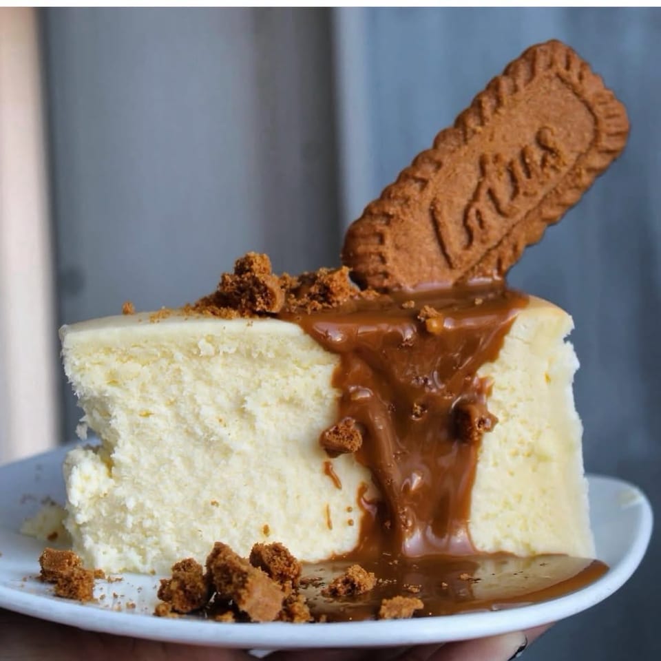 Cheesecake topped with cookie butter, cookie crumbs, and a biscuit.